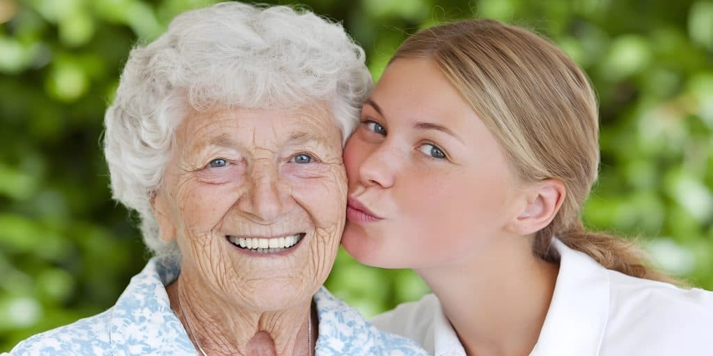 aging parent being kissed by grand daughter 